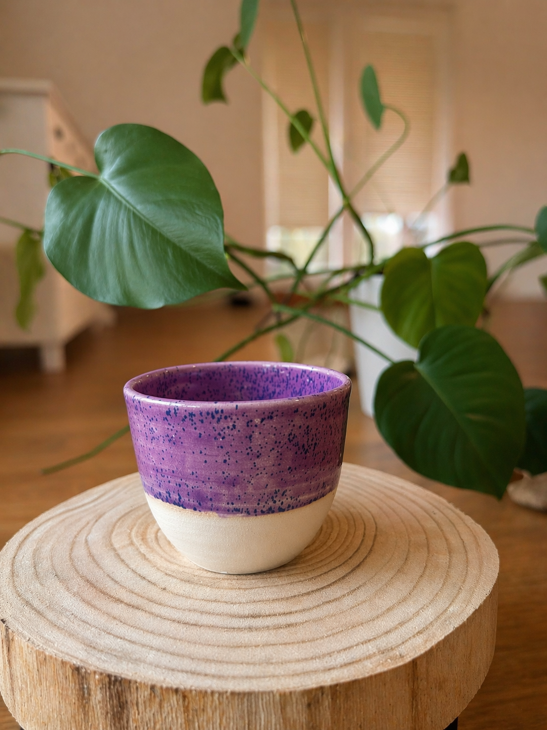Fialový keramický kalíšek na dřevěné podložce doma